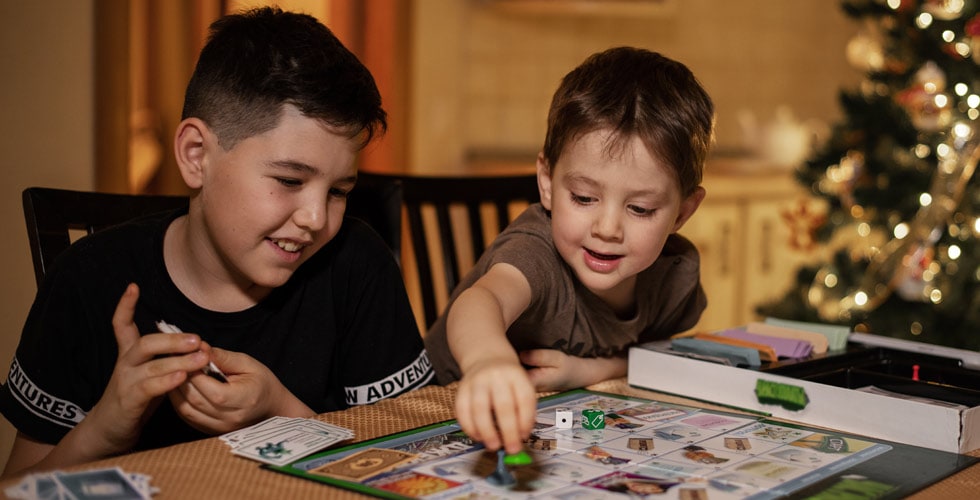 dois meninos sorrindo enquanto mexe em peças na mesa representando os melhores jogos de tabuleiro modernos