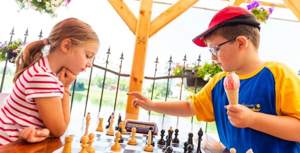 crianças sentadas em lugar aperto jogando representando a história do xadrez