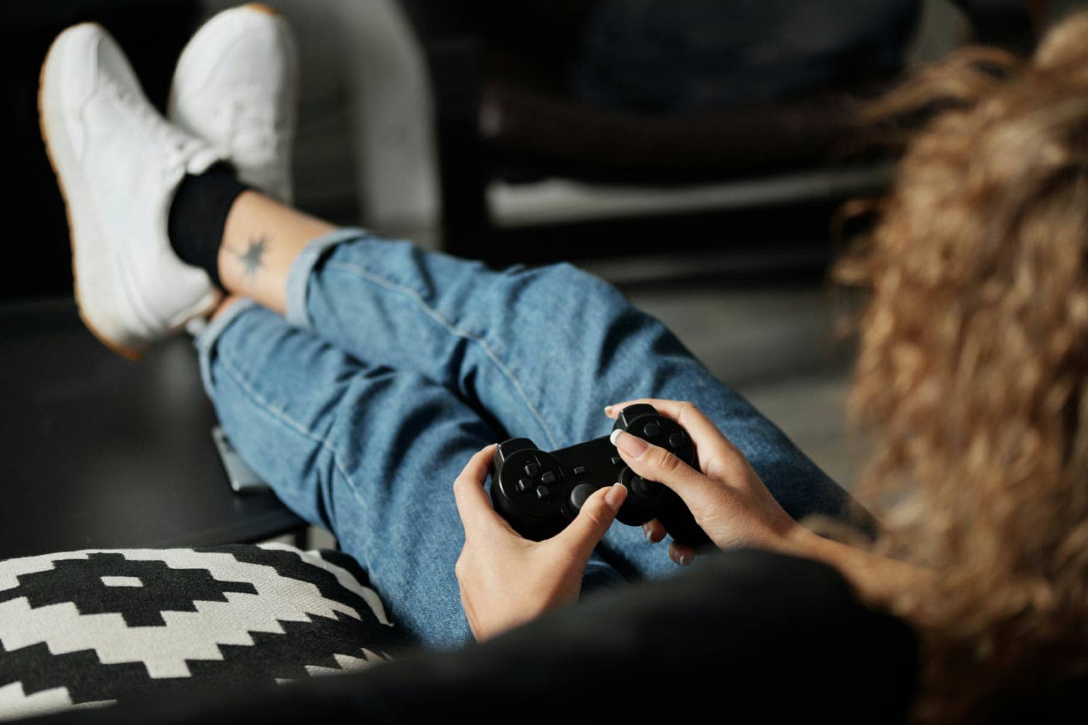 pessoa sentada em sofá segurando controle representando quem inventou o videogame